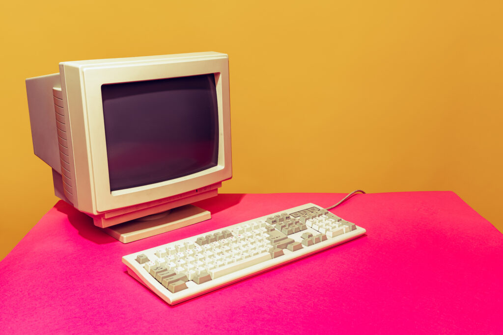 vintage computer and keyboard with a colorful orange and hot pink background 